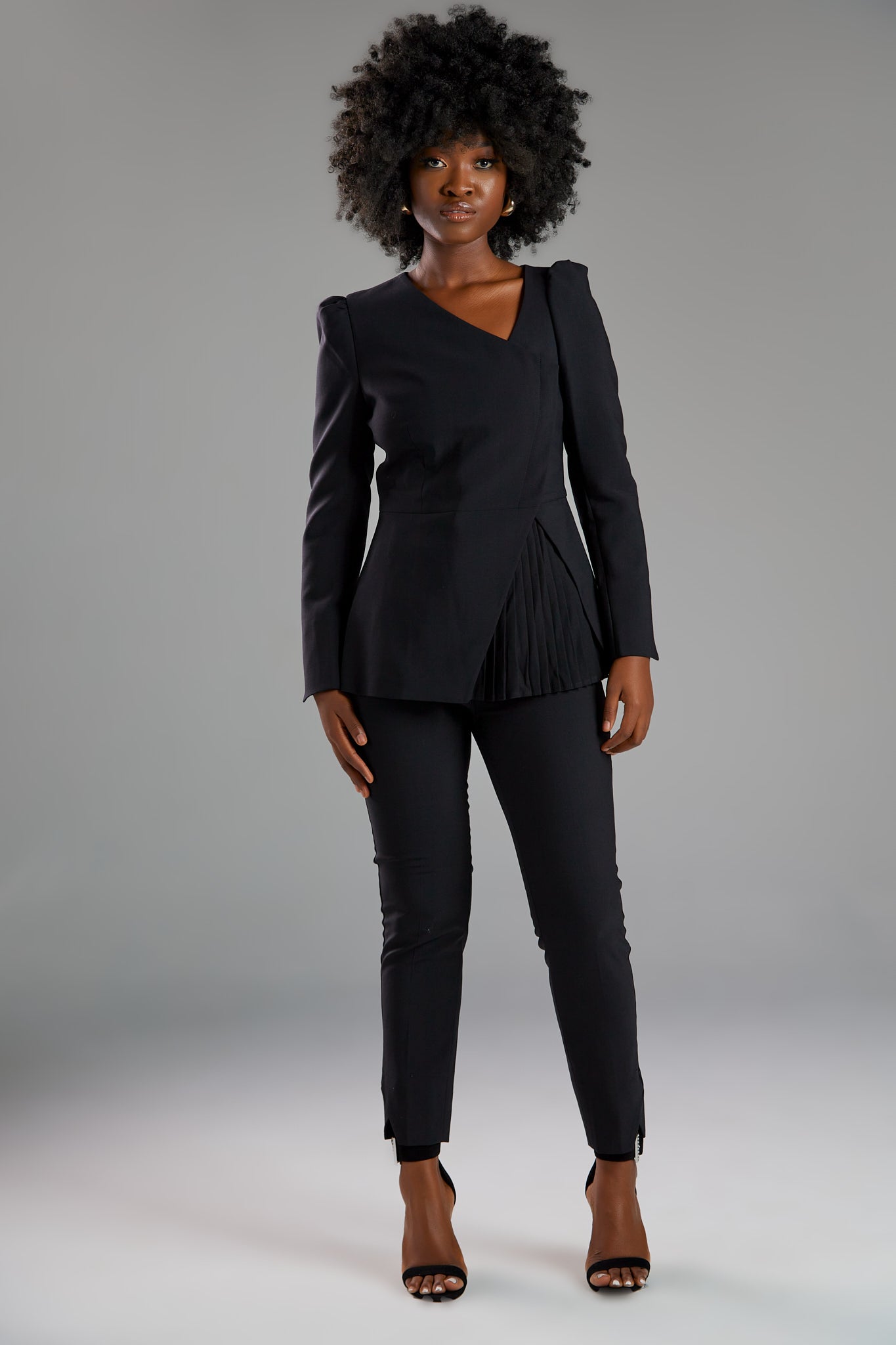 Seragyi's Liz Peplum Jacket in Women's Clothing line, made of wrinkle-resistant Italian Merino wool, showcasing Women's Jackets' sophistication, quality, and sustainability. A prime example of Women's Suits, it features an asymmetrical neckline, pyramid-cut sleeves, and a partially pleated peplum. Ideal for travel and versatile styling, from monochrome looks to skinny jeans and heels for evening wear.