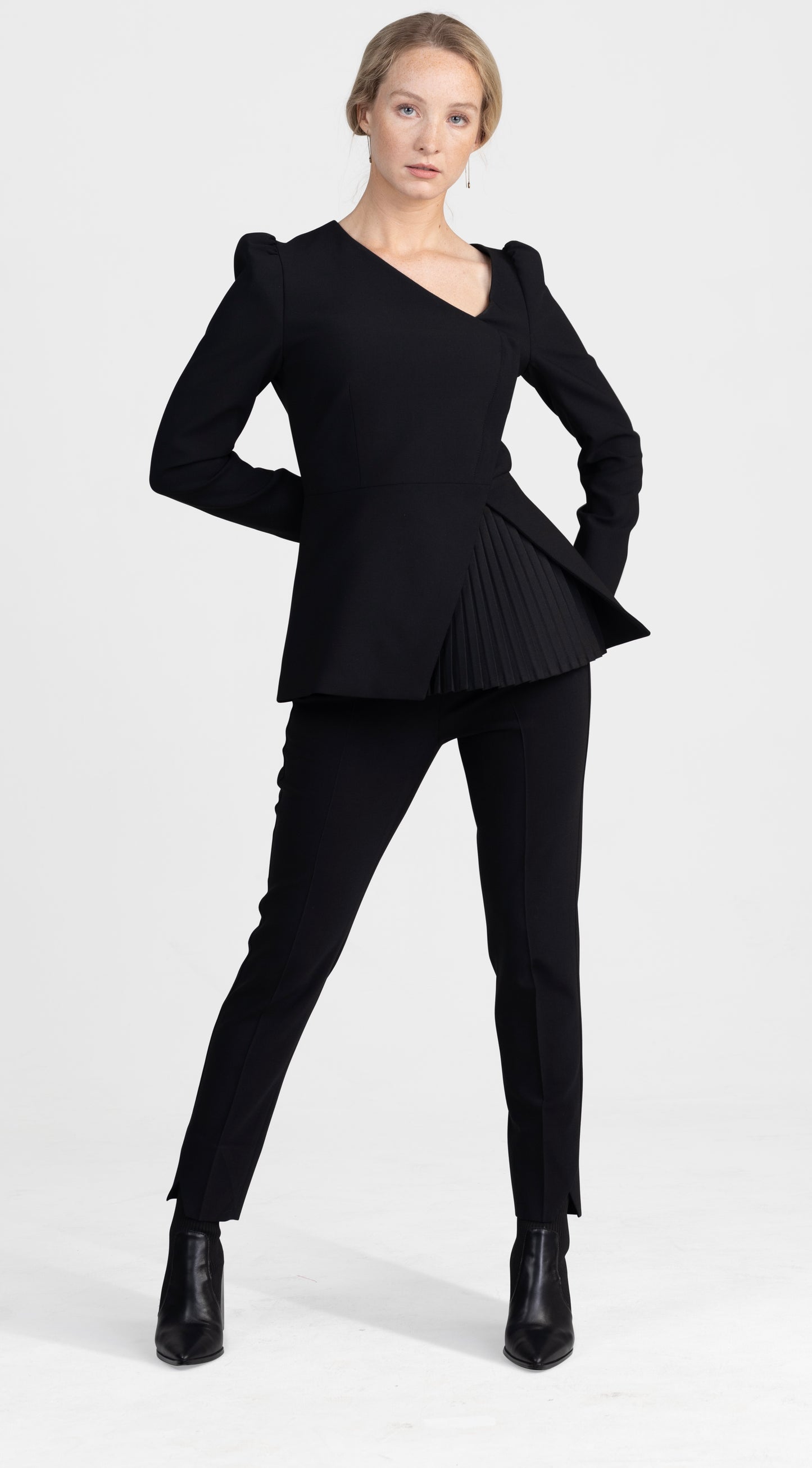 Seragyi's Liz Peplum Jacket in Women's Clothing line, made of wrinkle-resistant Italian Merino wool, showcasing Women's Jackets' sophistication, quality, and sustainability. A prime example of Women's Suits, it features an asymmetrical neckline, pyramid-cut sleeves, and a partially pleated peplum. Ideal for travel and versatile styling, from monochrome looks to skinny jeans and heels for evening wear.